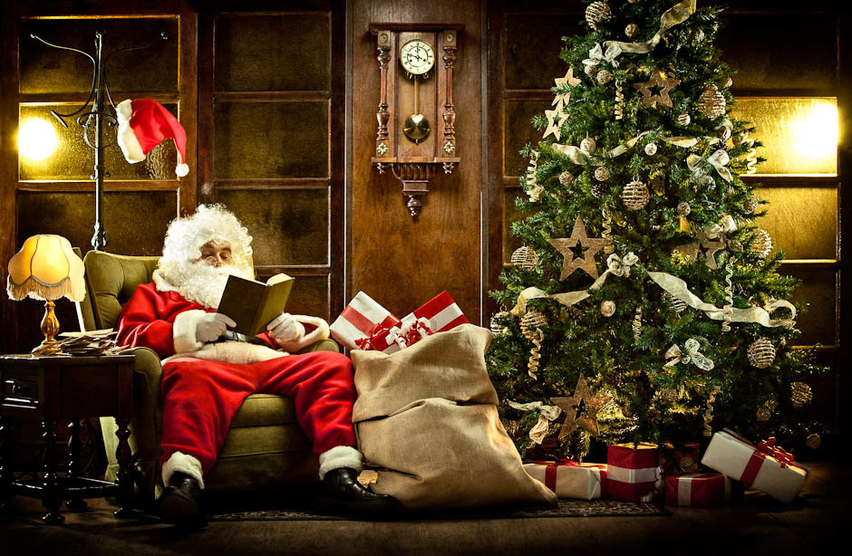 santa claus at home relaxing reading a book near christmas